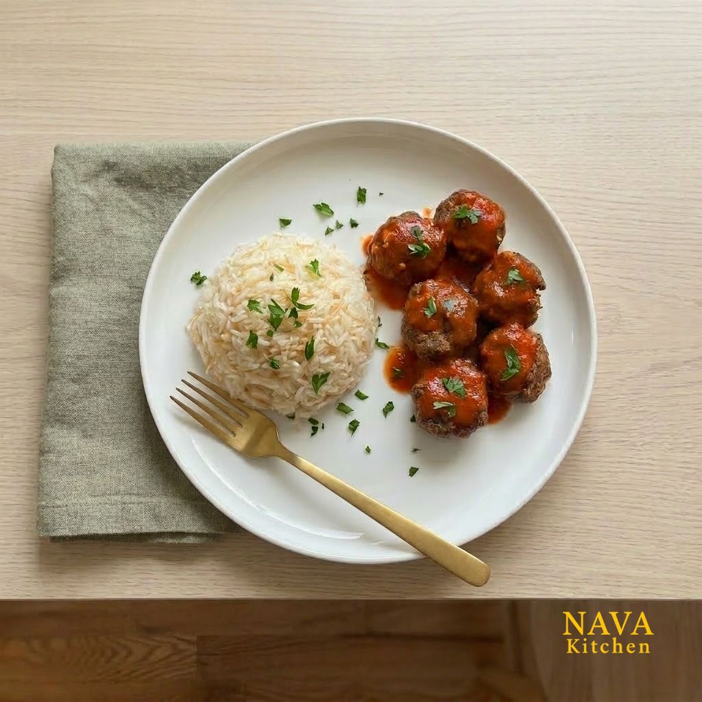 Oven-baked beef meatballs with tomato sauce served with butter rice and parsley on a white plate.